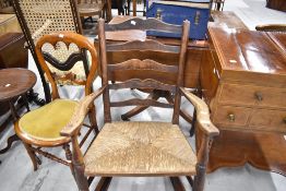 An early 20th century oak framed rocking chair with ladder back and rush seat