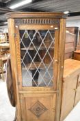 An Old Charm style floor standing corner cupboard having leaded light effect top section with carved