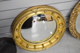 A Victorian butlers mirror having convex glass with gilt carved and decorated frame