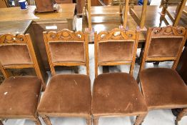 A set of four early 20th century oak framed dining chairs having turned legs and carved oak backs