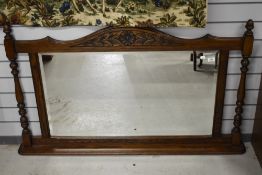 An early 20th century over mantel mirror having bevel edged glass and oak frame with carved details