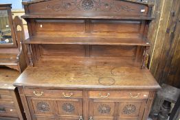 An oak breakfast bar dresser base with individual carved floral panel cupboard doors and plate