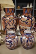 A pair of Japanese Imari baluster vases, decorated with garden vignettes and birds of paradise,