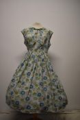 A 1950s floppy cotton day dress having pleated skirt and tie detail to neckline, with floral
