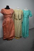 Three vintage 1960s evening gowns, including gold dress and jacket with gold tone floral detailing.