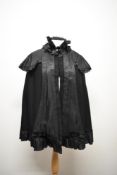 A late Victorian/ early Edwardian cape having ruffled detail to neckline and hook and eye