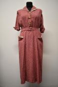 A late 1940s cotton dress having novelty pattern on pink ground with white accents to pockets and