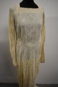A 1940s cream brocade wedding dress having full length sleeves, self covered buttons to back with