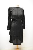 A 1930s black textured dress having geometric type pattern, full length sleeves with gathered cuffs,