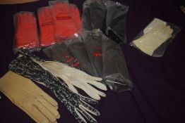 A selection of vintage gloves, most in original packaging, including red and black faux leather.