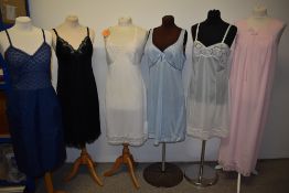 Five vintage nylon slips, one still having tags and a pale pink nightdress with lace to bodice.