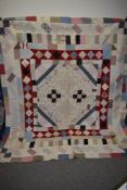 A 19th century patchwork quilt, using brightly patterned, floral and block fabrics with plain