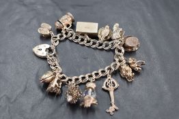 A silver charm bracelet having padlock clasp and 13 white metal and silver charms including cased £1