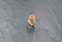 A yellow metal and agate ring, the domed cabochon within a pierced foliate, surround, the shank