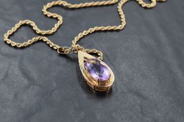 A large amethyst pendant in a yellow metal tear drop shaped open mount stamped 9ct on a 9ct gold