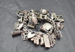 A silver charm bracelet having padlock clasp and 30 white metal and silver charms including Tower of