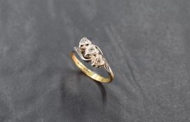 An 18ct gold and diamond three stone ring, the three small diamond brilliants illusion-set within