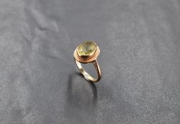 A 9ct gold and green stone ring, the central raised oval-cut light green stone within a rubbed-