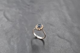 A sapphire and diamond cluster ring in a claw set basket mount to knife blade shoulders on an 18ct