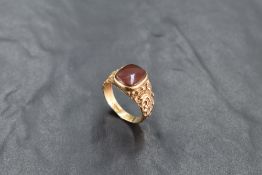 A 9ct gold and red agate signet ring, the rounded rectangular red agate matrix between scroll