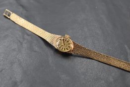 A ladies 9ct gold cased wristwatch, the oval dial with baton hour markers between the Milanese