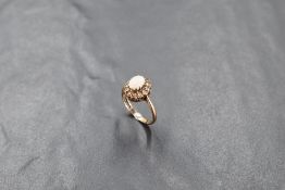 A 9ct gold opal and white stone dress ring, the central oval milky opal enclosed by twelve small