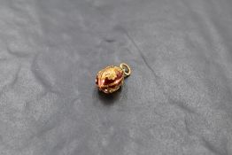 An enamelled yellow metal egg pendant stamped 750, badly damaged and missing most of enamel,