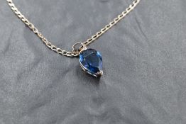 A pear shaped blue stone pendant, possibly tanzanite in a white metal mount on a silver chain