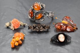 An amber set white metal bangle, of sinuous foliate form set with three large amber cabochons,