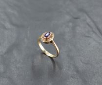 An oval amethyst ring having seed pearl surround in a collared mount on a 9ct rose gold loop, size N
