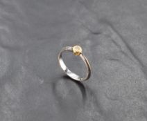 A diamond solitaire ring, approx 0.075ct in a yellow gold collared mount on an 18ct white gold loop,