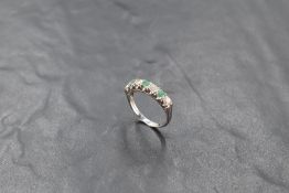 An 18ct white gold diamond and emerald ring, having a linear arrangement of four diamonds