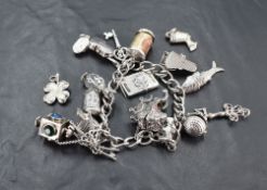A silver and white metal charm bracelet, of traditional form with various suspended charms including