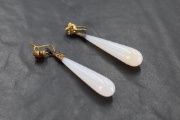 A pair of chalcedony elongated tear drop earrings with yellow gold caps and loop fittings, one