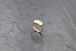 A 9ct gold opal and seed pearl ring, the three oval opal cabochons interspersed with small seed