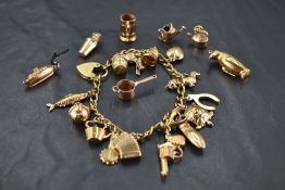 A yellow metal charm bracelet having padlock clasp stamped Hollow Gold, 18 x 9ct gold charms