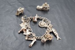 A silver charm bracelet having padlock clasp and thirteen charms (2 loose) including articulated