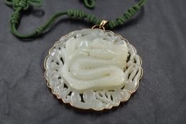 A modern Chinese carved pale green stone pendant, of lobed circular form, carved and pierced in