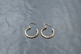 A pair of yellow metal earrings, of circular form with hinged clasps and engine-cut fluted