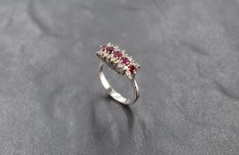 A ruby and diamond triple row ring having central row of five diamonds within a border of diamond