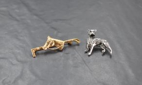 A yellow metal horse and riding crop form brooch, sold together with a white metal boxer dog