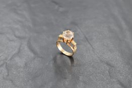 A yellow metal and white stone ring, the large raised brilliant-cut white stone, claw set between