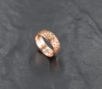 A 9ct rose gold wedding band of broad form having engraved floral decoration, size P & approx 3.8g