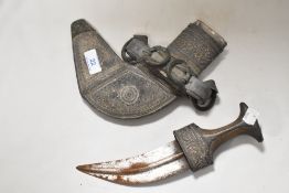 An antique Oman Khanjar dagger having ornate silver tone embossed detailing and fine wire to wood