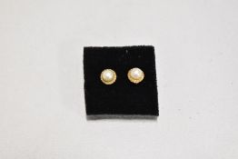 A pair of cultured pearl yellow metal stud earrings stamped 18 having screw on butterfly backs,