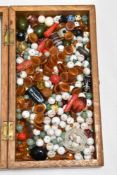 A wooden case full of vintage beads, predominantly coloured glass.