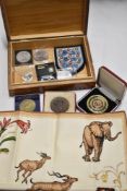 A wooden case containing collectable coins and currency, including a Football Association medal