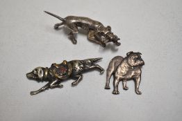 A silver and gold tone setter or flat coat retriever brooch having saddle bag with red cross emblem,