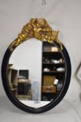 A modern oval hall way mirror with cherub figures to top of frame
