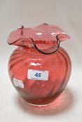 A Dartington cranberry glass vase having fluted rim and ribbed body, marked to underside.